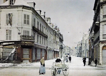 A woman with a cart filled with milk cans in Rue de Vesle and a man with another cart in Rue de Talleyrand behind her, Reims, France, March 3, 1917